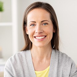 Woman in grey shirt sitting on couch and smiling