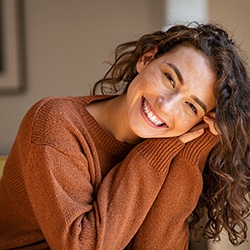 Woman in orange sweater leaning forward and smiling